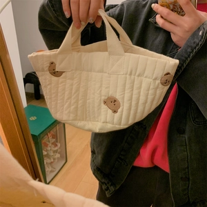 Close-up of quilted cream bucket bag featuring cute brown bear embroidery details