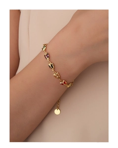 Detail of a gold butterfly bracelet with colorful resin charms worn on a woman's wrist