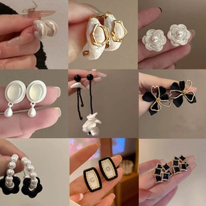 Detailed close-up of fashion earrings with pearls and floral motifs in gold and black