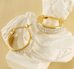Detailed macro of gold hoops with double rows of crystals on a white classical bust