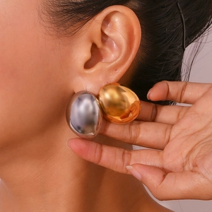 Close-up of chunky gold and silver waterdrop earrings on ear highlighting polished finish