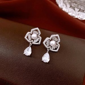 Macro detail of silver flower earrings with pearls and pear-shaped crystal pendants