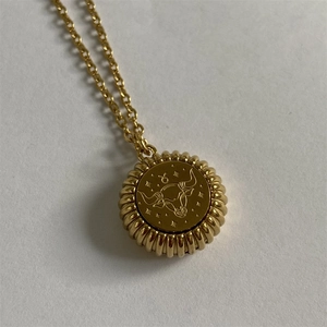 Detailed close-up of a gold Taurus zodiac medallion necklace with bull emblem