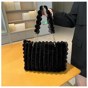 Detail of black faux fur tote bag with vertical stripes and plush ball chain handle
