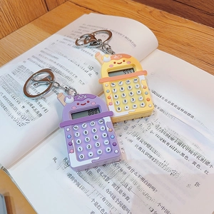 Mini calculator keychains in purple and yellow on a book, creative bag accessories