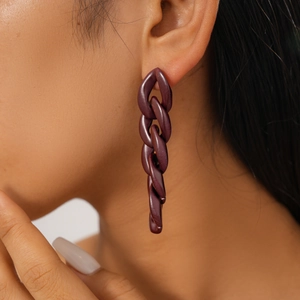 Close-up of dark reddish-brown acrylic chain link earring worn on a model's ear