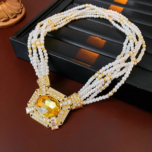 Dettaglio di una collana di perle vintage multistrato con pendente in cristallo dorato