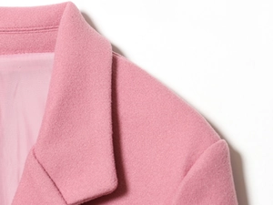 Dettaglio del risvolto e della trama del tessuto in lana rosa di un blazer raffinato