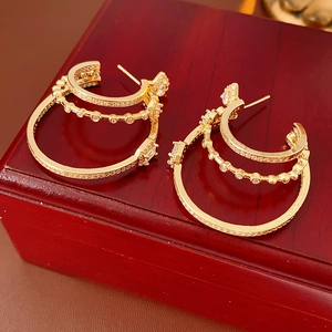 Detail of layered gold hoop earrings with sparkling diamonds on a mahogany jewelry box