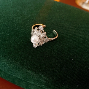 Macro shot of silver open ring featuring a white pearl and intricate hollow lace details