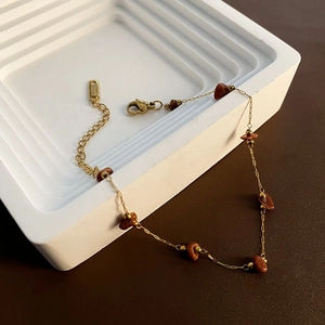 Minimalist gold stainless steel beaded necklace with brown natural stones on display