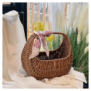 Detail of hand-woven dark brown rattan basket bag featuring a lilac patterned silk scarf