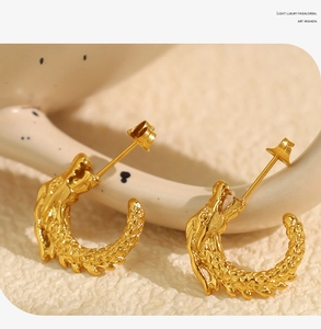 Detailed view of C-shaped gold dragon scale textured titanium steel hoop earrings