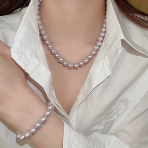Detailed view of layered lavender pearl necklace and bracelet on a white shirt