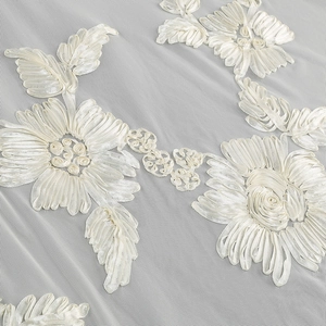 Close-up of white ribbon floral embroidery on delicate mesh fabric dress detail