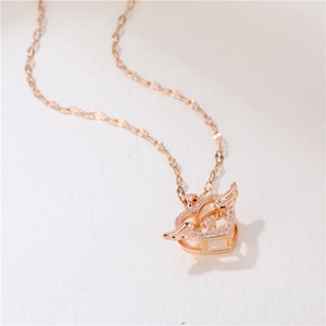 Rose gold angel wing heart necklace with sparkling gems on a soft textured background