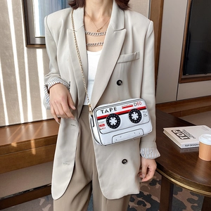 Retro white cassette tape crossbody bag with gold chain strap worn with a beige blazer