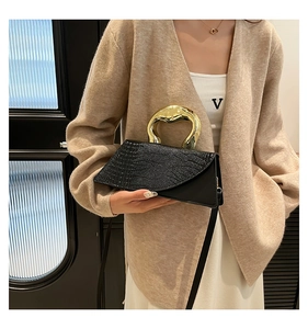 Detail of black crocodile texture handbag with gold metal handle and crossbody strap