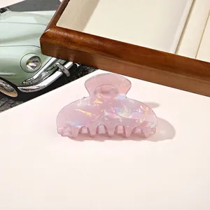 Detail of elegant pink marble acrylic hair claw clip on a vintage wooden tray