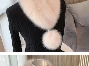 Detail of light pink faux fur scarf with pom-poms on a black textured sweater