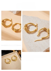 Macro view of gold-plated stainless steel hoop earrings with textured beads and polished spheres