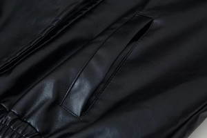 Close-up of black PU leather jacket showing detailed pocket stitching and smooth texture