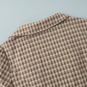 Close-up of brown plaid shirt collar with detailed stitching and soft cotton texture