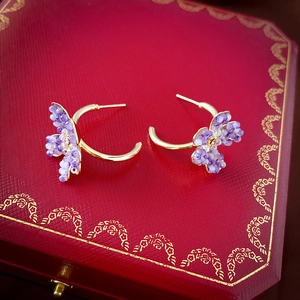 Macro detail of gold flower C-shaped earrings with purple crystals on jewelry box