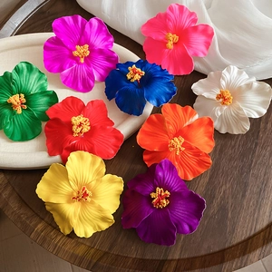 Top view of colorful realistic hibiscus flower hair clips on a tropical wood background