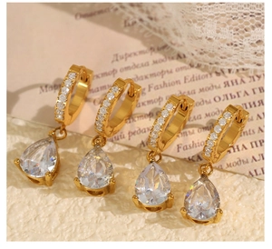 Détail de boucles d'oreilles dorées avec zircons en goutte et décor dentelle