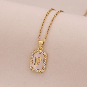 Vue détaillée du pendentif carré doré avec lettre P, nacre et bordure en cristal