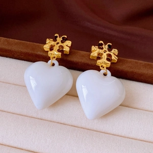 Macro view of vintage heart pearl earrings with gold plating on soft velvet padding