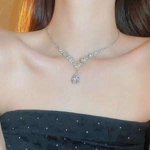 Close-up of elegant silver teardrop pendant necklace with zircon stones on a model
