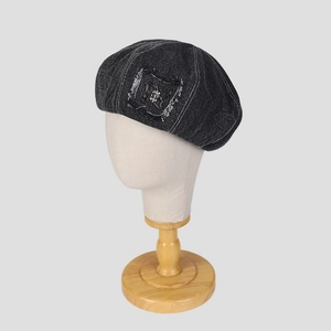 Denim beret in black wash with raw edge patch and butterfly metal accent detail