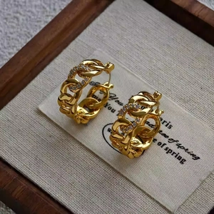 Gold chain link hoop earrings with sparkling zircon stones on a rustic display pad