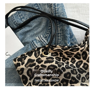Detailed close-up of leopard print canvas tote bag with black straps and metal eyelets