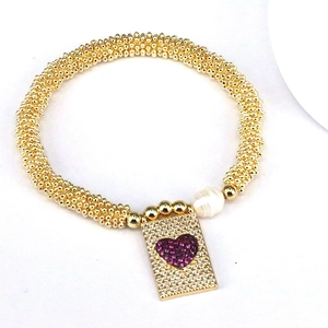 Detail of golden beaded bracelet with purple heart pendant and freshwater pearl accessory