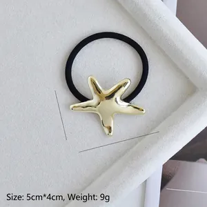 Detail of golden starfish hair tie showing 5x4cm dimensions and 9g weight on white tray
