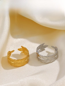 Detail showing gold and silver feather rings on white silk fabric with adjustable band design