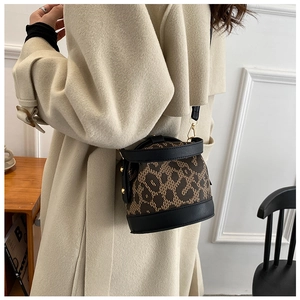 Chic leopard print bucket bag with black leather trim worn by model in beige coat
