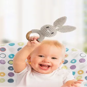 Handmade crochet bunny baby rattle with a natural wooden ring and soft grey knitted fabric