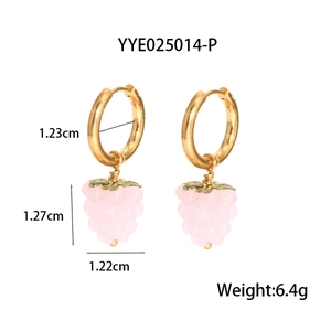 Gros plan de créoles dorées avec pendentifs de raisin rose et feuilles vertes sur fond blanc