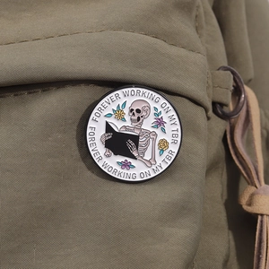 Close-up of enamel skull book pin on canvas bag with Forever Working On My TBR text