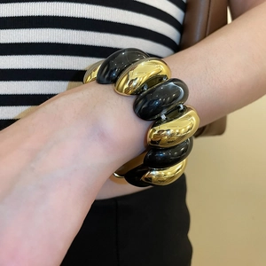 Detail view of bold acrylic and gold metal chunky bracelet on a female wrist