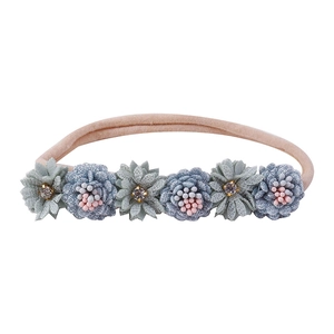 Detailed macro view of handmade infant floral headband with soft petals and sparkling crystals