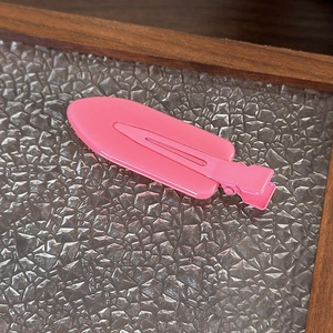 Dettaglio di un fermaglio per capelli rosa opaco su una superficie in vetro goffrato