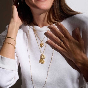Detail of elegant gold layered necklaces and bracelets with ancient Greek pendants on a model