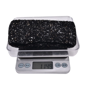 Close-up of a thick black speckled knit beanie showing a weight of 114.9g on a scale