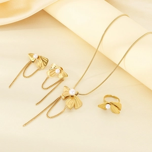 Detail of gold butterfly jewelry set with pearls and tassels on silk background