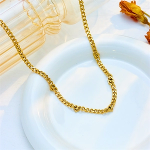 Elegant gold Cuban chain necklace with heart pendant on a white ceramic dish